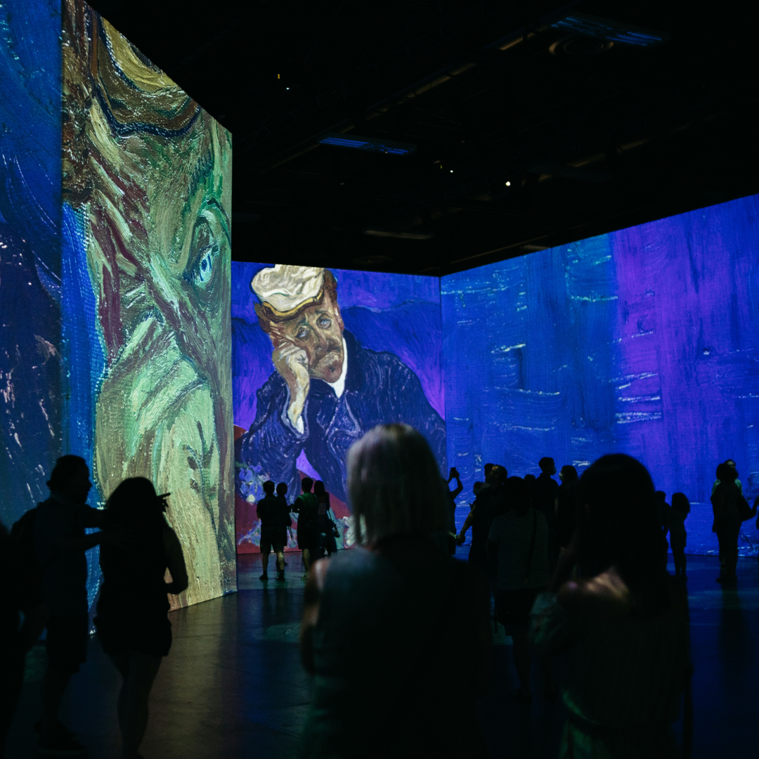 Visitors silhouetted against projected artwork at an immersive live event experience